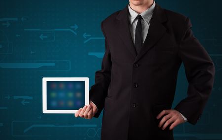Young businessman holding a white modern tablet with blurry apps