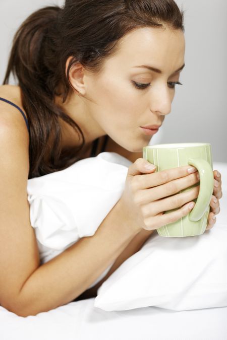 Young woman enjoying a coffee in bed