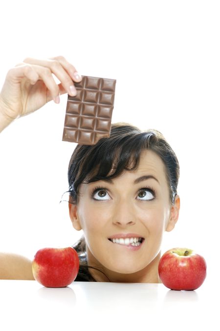 Young woman torn between a chocolate bar and fresh apple