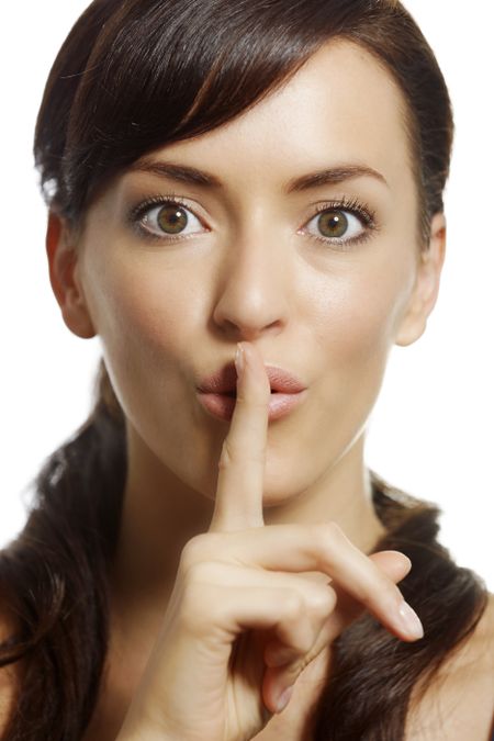 Woman holding a finger over her lips to shush someone.