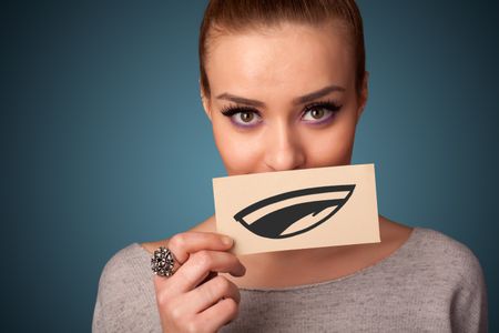 Pretty young girl holding white card with smile drawing on gradient background