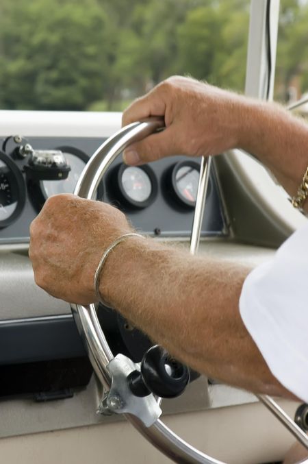 Strong hands of mature man piloting riverboat