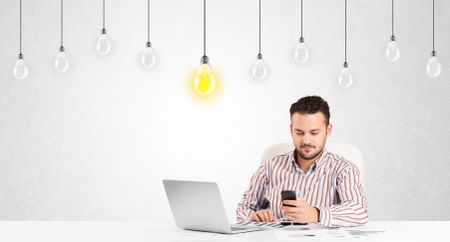 Business man sitting at table with bright idea light bulbs