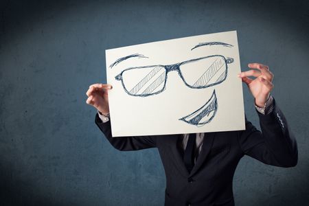 Young businessman holding a paper with smiley face in front of his head