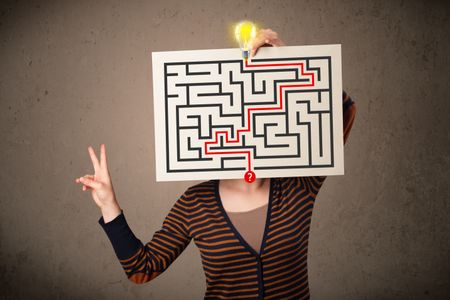 Young woman holding a paper with a labyrinth on it in front of her head