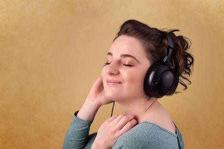 Pretty young woman with headphones listening to music with empty space