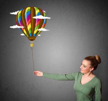 Young woman holding a balloon drawing with clouds