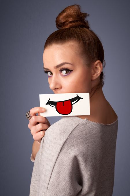Happy pretty woman holding card with funny smiley on gradient background