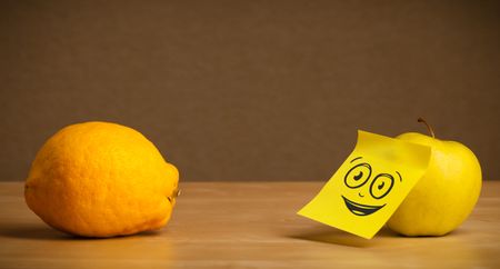 Apple with sticky post-it note looking at lemon