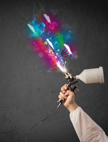 Worker with airbrush and colorful abstract clouds and balloons concept