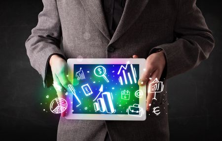 Young person holding white tablet with graph and chart symbols