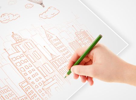 A person drawing sketch of a city with balloons and clouds on a plain paper 