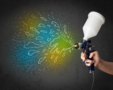Worker with airbrush gun paints colorful lines and splashes concept