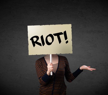 Young woman holding a demonstration board with riot sign in front of her head