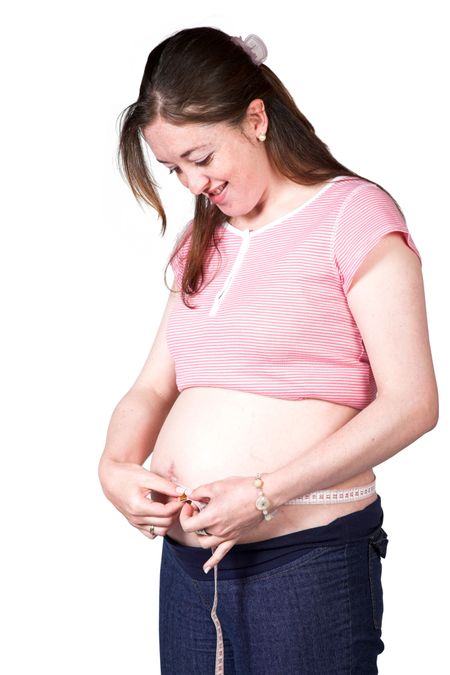 pregnant woman measuring her belly over white