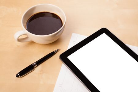 Tablet pc with copy space and a cup of coffee on a wooden work table close-up