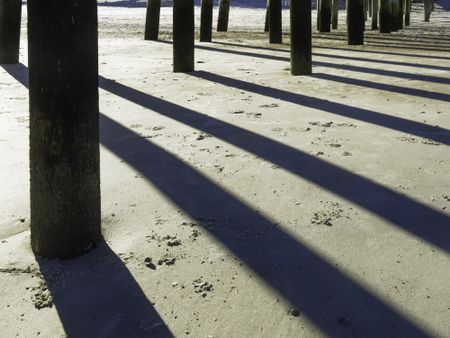 Afternoon shadows of pylons under long pier at Fernandina Beach, Florida