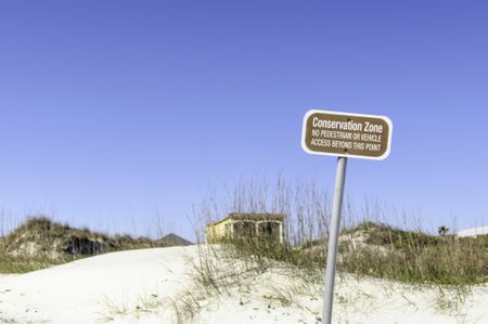 Conservation sign on dune at beach near St. Augustine, Florida, USA: "Conservation Zone / No pedestrian or vehicle access beyond this point" (selective focus)