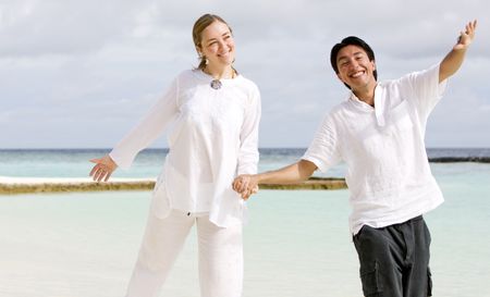 Beautiful young couple in love walking and smiling at the beach