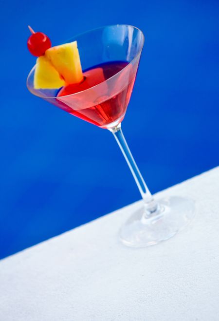 cocktail with pinapple and cherry on edge of pool