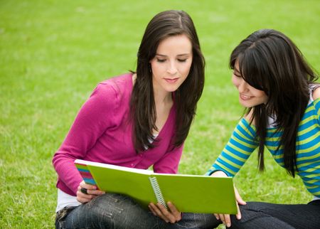 Beautiful girls studying with their notebooks - smiling outdoors