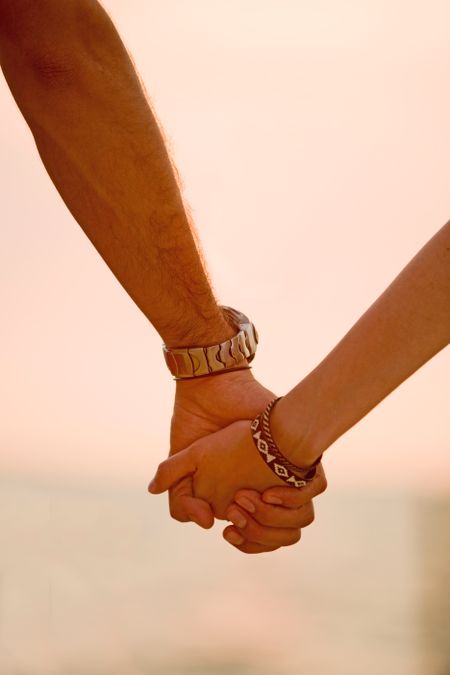 couple holding hands at sunset in a romantic setting