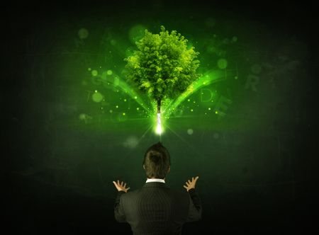 Young businessman standing with a glowing tree and letters above his head