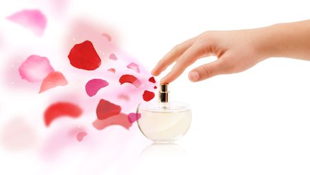 close up of woman hands spraying rose petals from beautiful perfume bottle