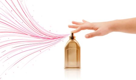 close up of woman hands spraying colorful lines from beautiful perfume bottle
