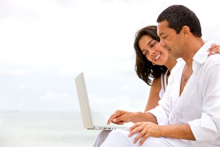 happy beach couple on a laptop during vacation