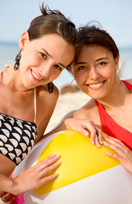 Happy friends smiling at the beach with a ball