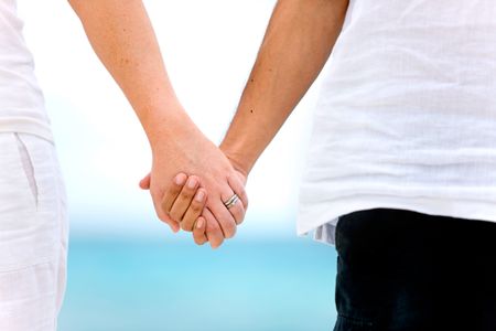 couple holding hands by the sea in a romantic setting