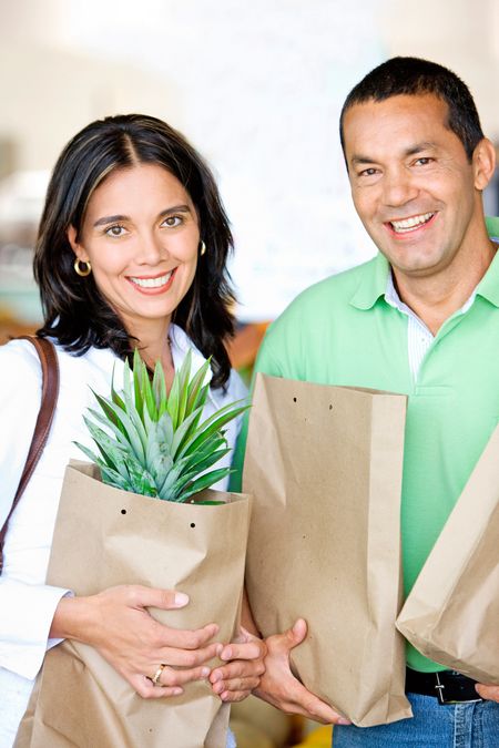 Beautiful couple in love smiling - shopping in supermarket with bags