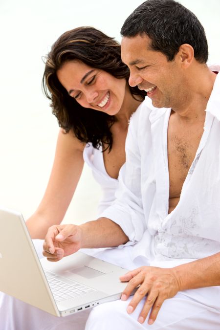 happy beach couple on a laptop during vacation