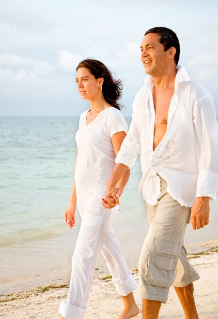 happy couple walking at the beach dressed in white