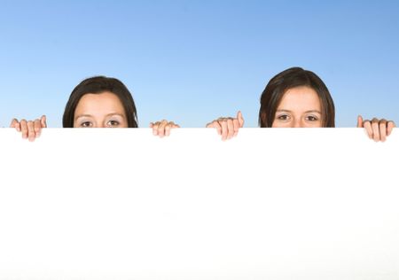 beautiful twins holding a white board with the sky in the background - clipping path included in the file so you can easily replace the sky for another background