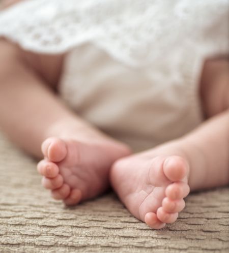 feet detail of a baby girl in christening dress