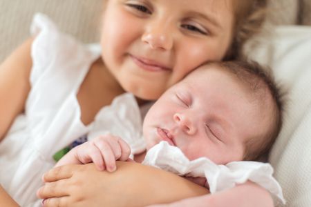 girl holding her newborn sibbling