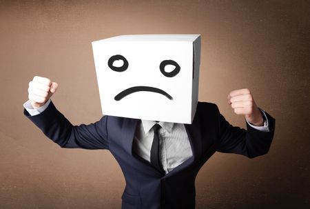 Businessman standing and gesturing with a cardboard box on his head with sad face