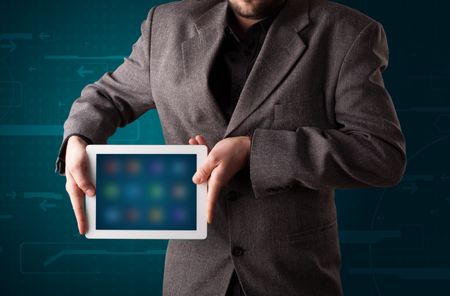 Young businessman holding a white modern tablet with blurry apps