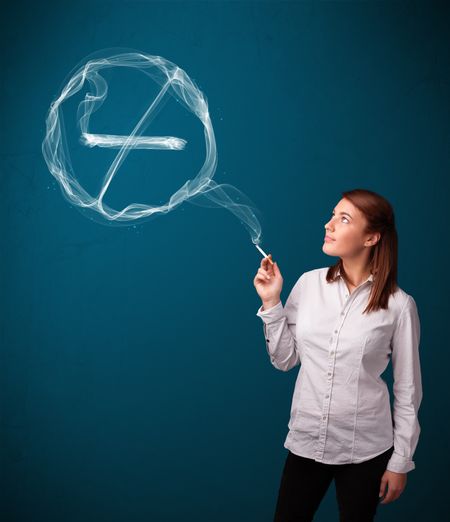 Pretty young lady smoking unheathy cigarette with no smoking sign