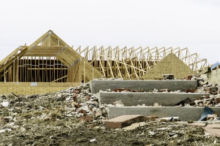 Contrast in tornado recovery: Foreground of abandonment with broken debris by concrete steps of blasted foundation in contrast with reconstruction of single-family house across the street