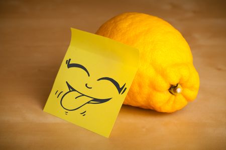 Drawn smiley face on a post-it note sticked on a lemon