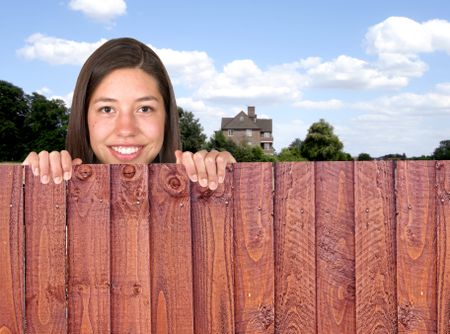 beautiful girl over a fence with a house in the background