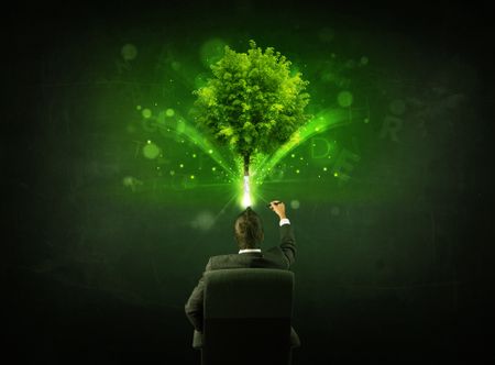 Young businessman sitting in office chair with a glowing tree and letters above his head