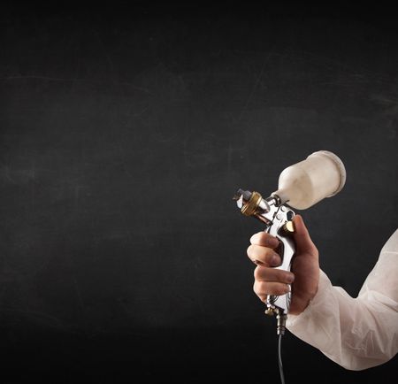 Painter works with airbrush gun and empty copyspace on dark background