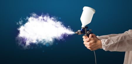 Painter with airbrush gun and white magical smoke concept