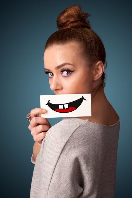 Happy pretty woman holding card with funny smiley on gradient background