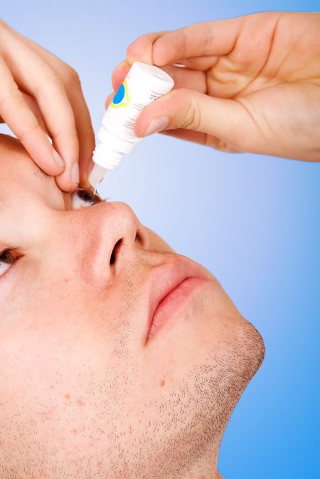 guy applying eye drops to his eye, focus is on face