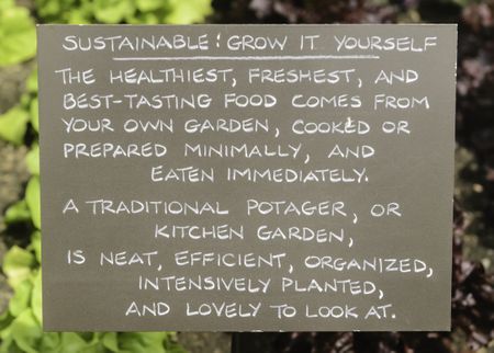 Encouragement for potential gardeners: Sustainability sign by rows of vegetables in botanic garden